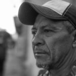 Black and white portrait of a thoughtful man in a cap on a street in Santiago de Querétaro.